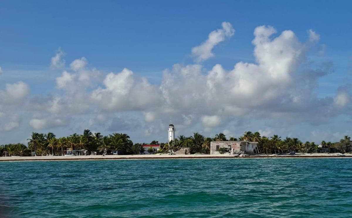 Cabo Catoche lighthouse on a palm-fringed sandbar seen from the sea