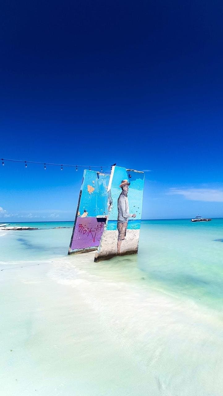 Painted art panel standing in the turquoise waters of Holbox beach