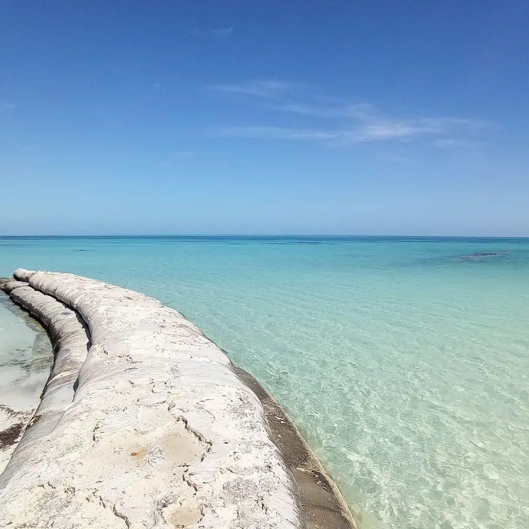 Narrow sandbar curving into crystal-clear turquoise water near Holbox