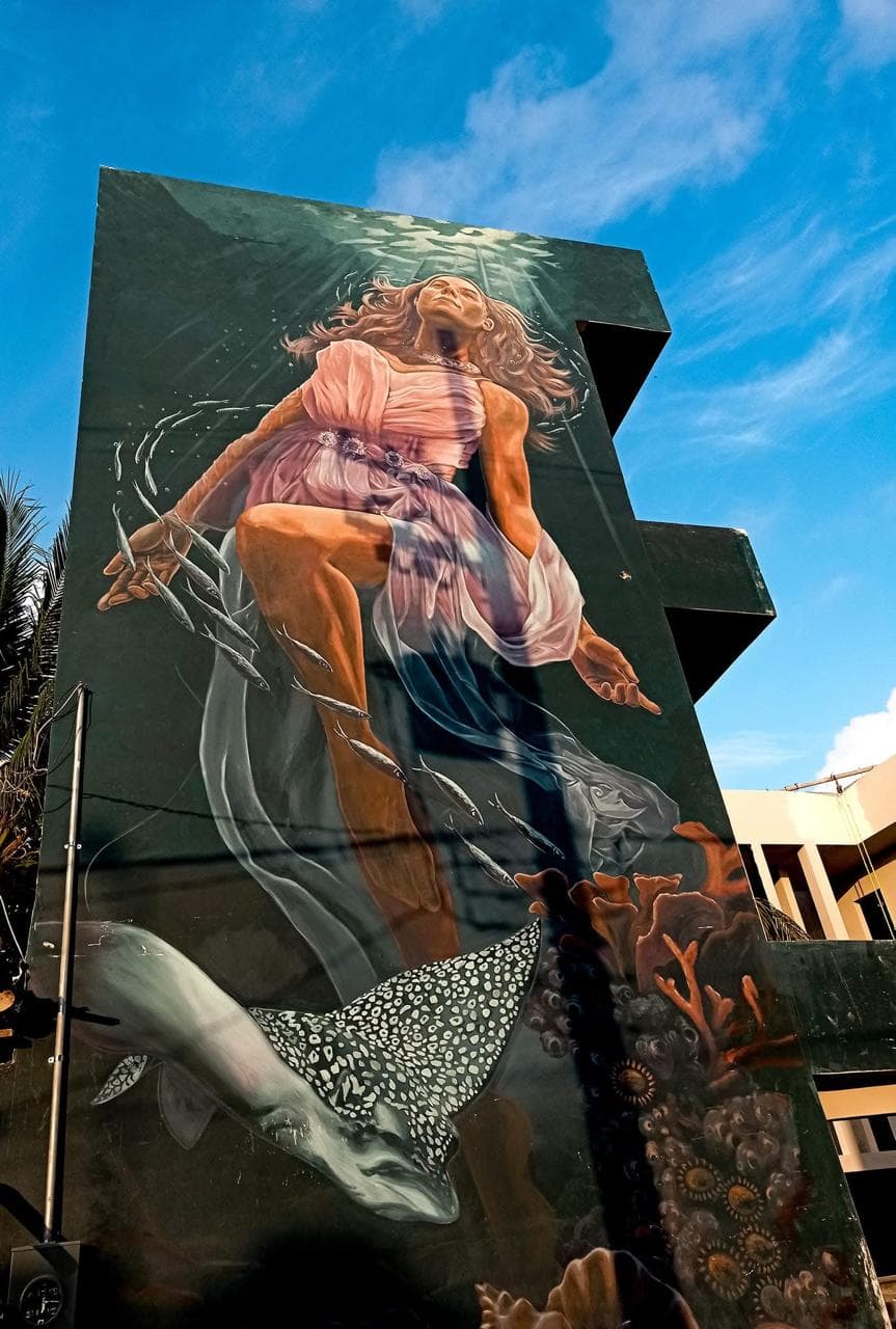 Large building mural of an underwater figure in Holbox