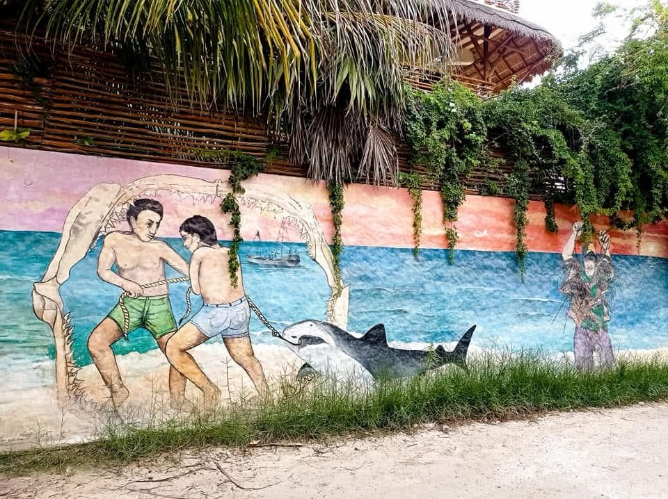 Mural of fishermen and a whale shark on a Holbox wall
